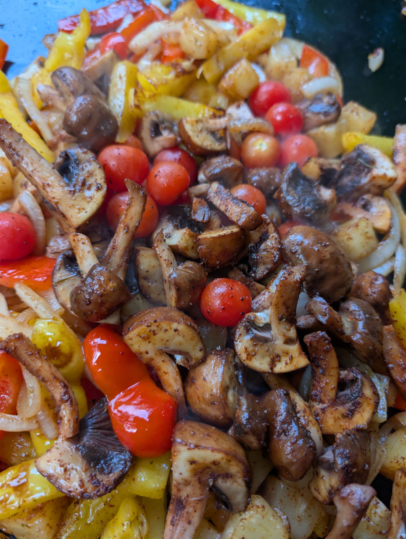 Everything mixed together on the Blackstone with mushrooms and cherry tomatoes added