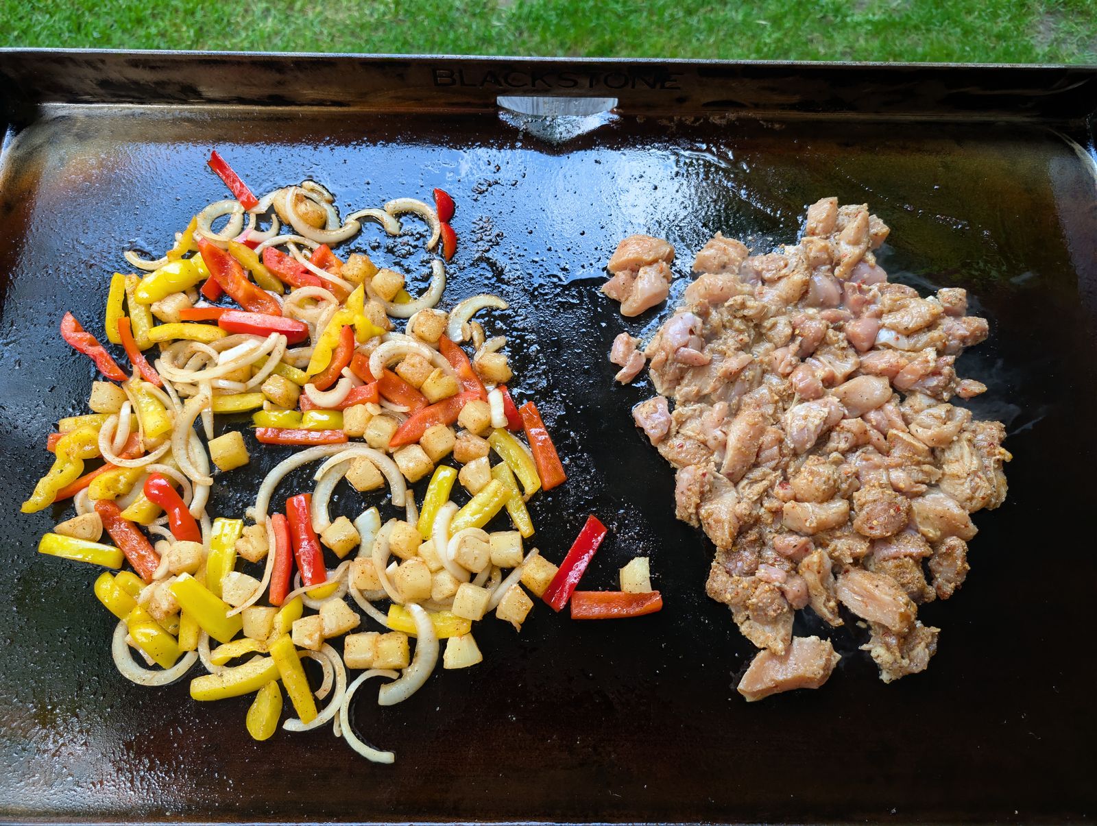 Overhead view of the Blackstone griddle showing vegetables on one side and marinated chicken on the other
