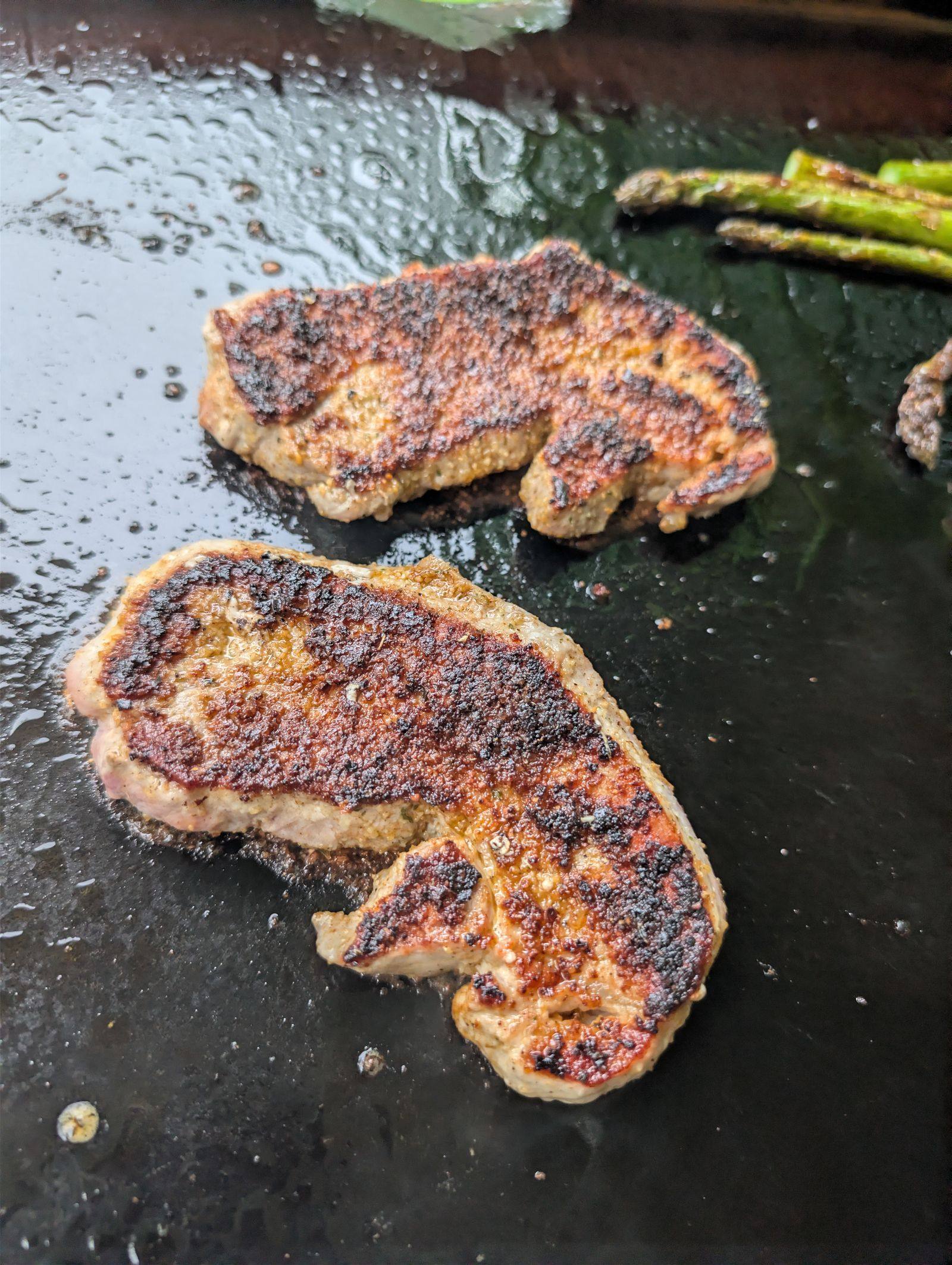 Cajun-seasoned pork steaks with a deep crust, ready to come off the Blackstone griddle
