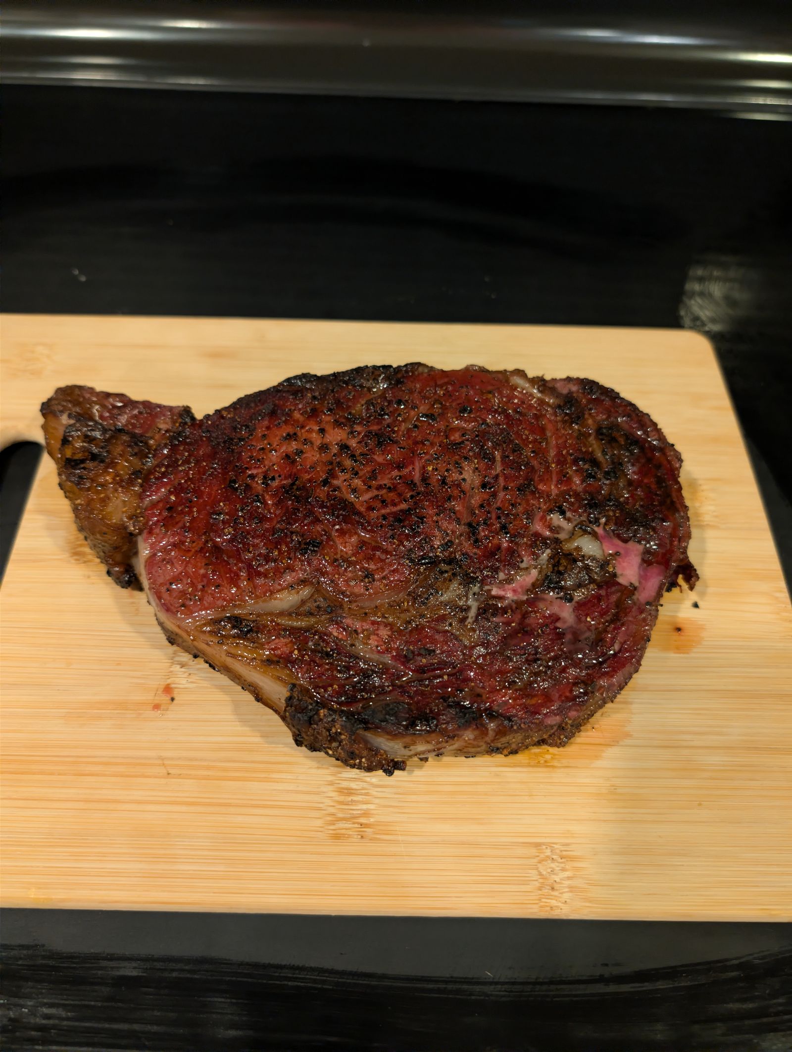Reverse seared ribeye with a dark mahogany crust resting on a cutting board