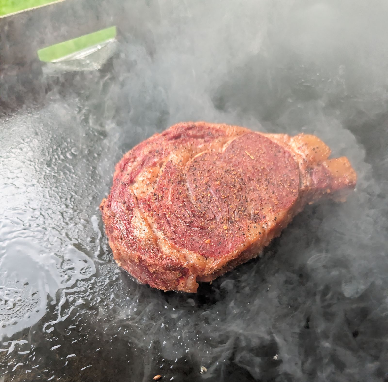 Ribeye searing on the Blackstone griddle with a hard crust forming